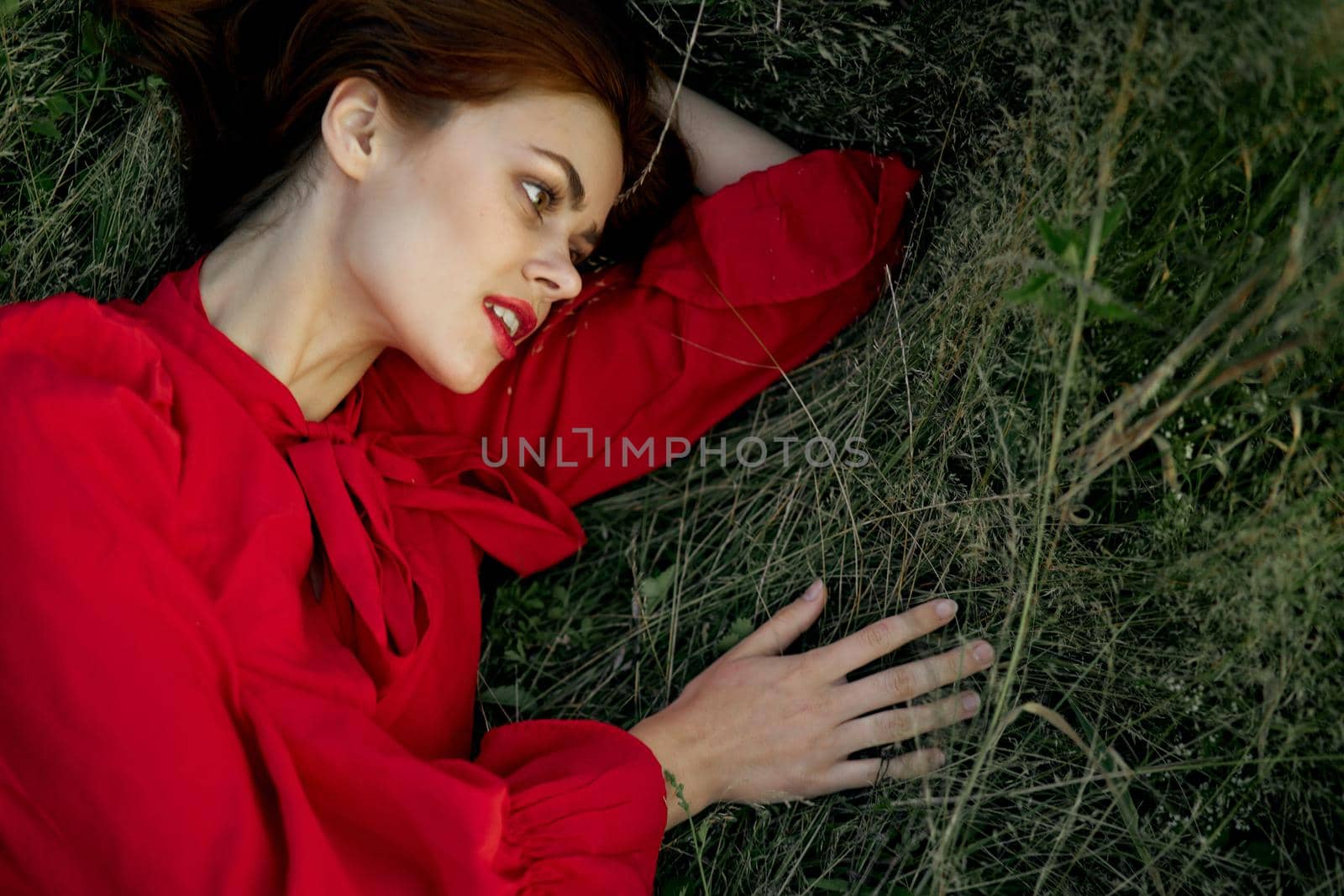 pretty woman in red dress lies on the grass sun summer nature. High quality photo