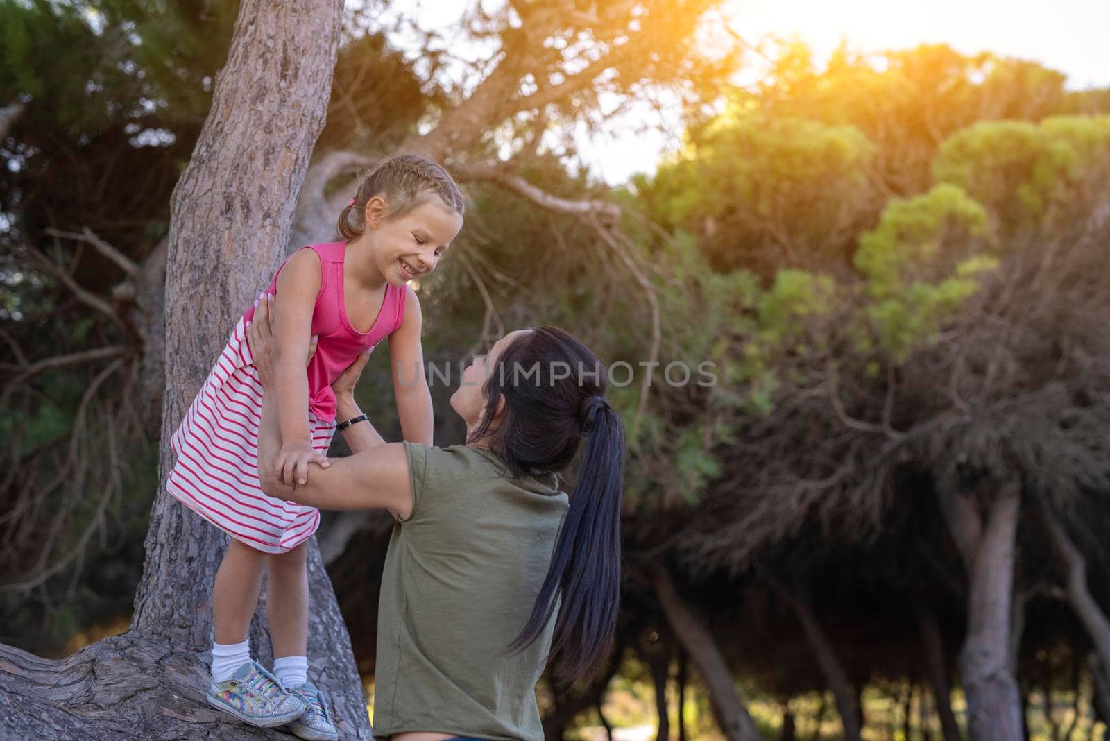 Beautiful mother and her little daughter outdoors. Beauty Mum and her Child playing in Park together at sunset. Outdoor Portrait of happy family. Mother's Day by Alexxoma