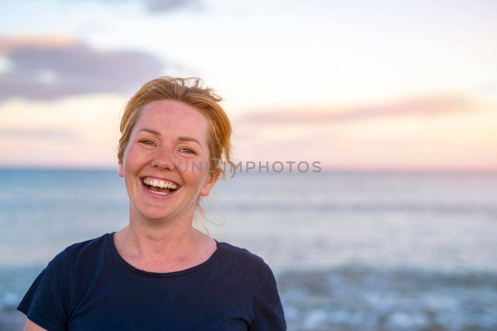 Young attractive white caucasian woman smiling and laughing on the beach warm summer evening.