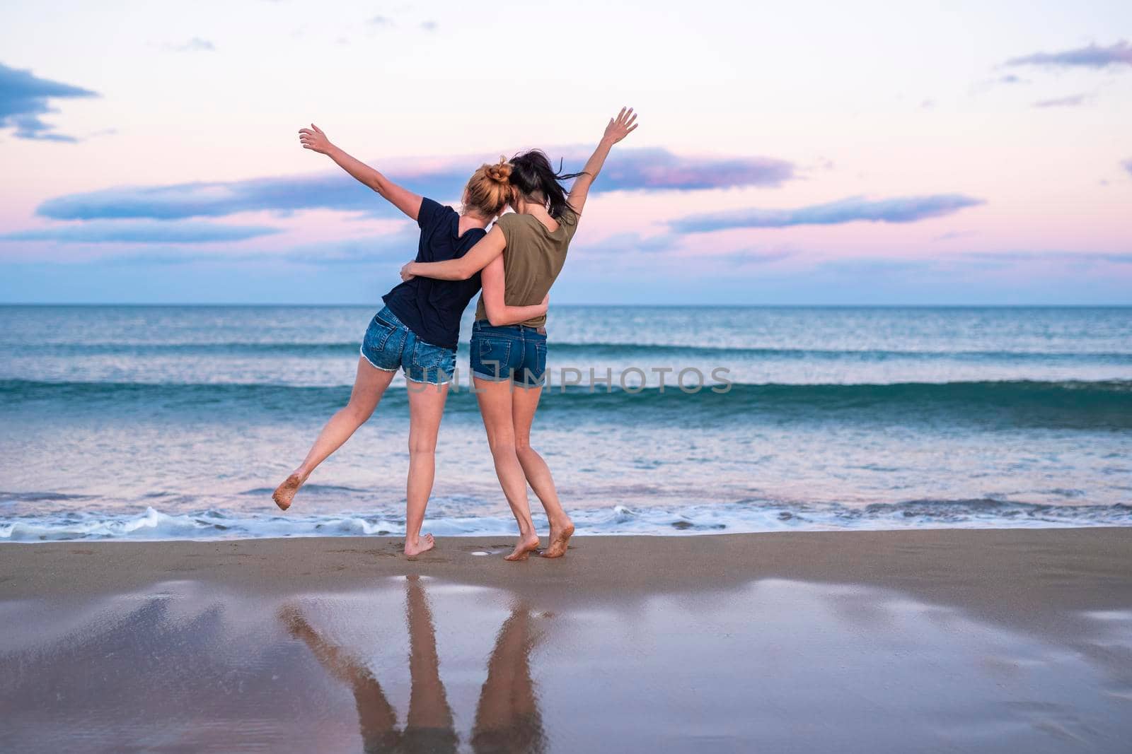 Two pretty young girls pretty best friend women having fun on their summer vacation on Mediterranean sea, mini denim shorts, amazing blonde and brunette hairs, traveling experience, happy emotions by Alexxoma