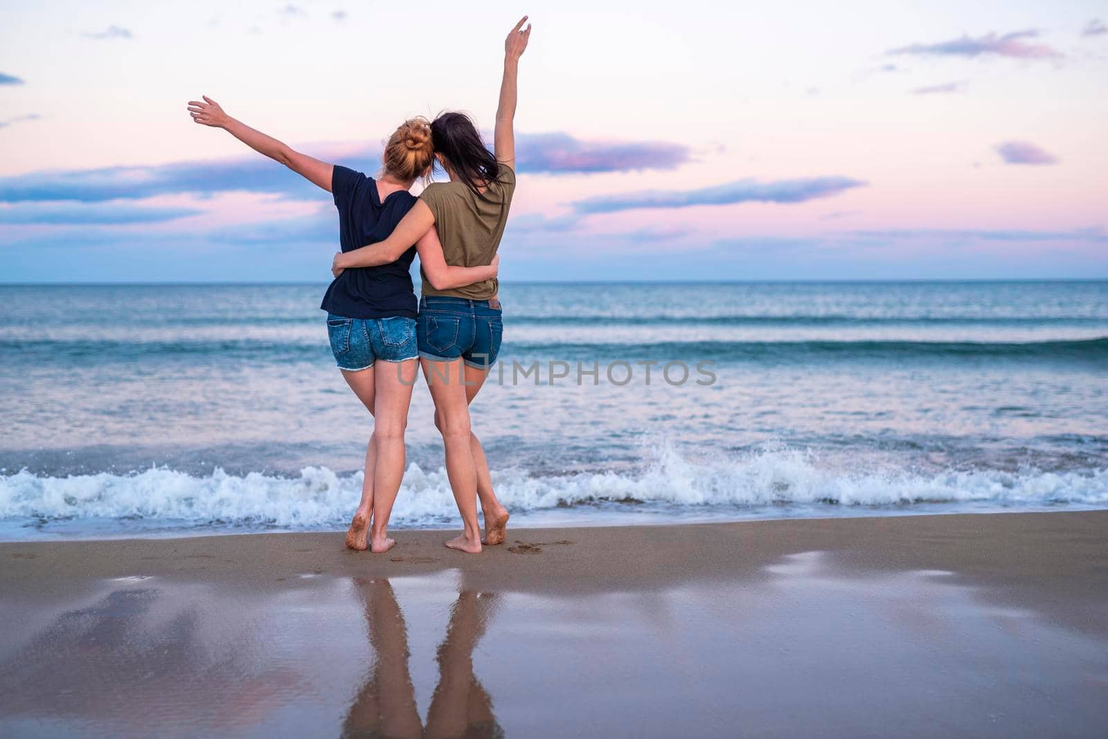Two pretty young girls pretty best friend women having fun on their summer vacation on Mediterranean sea, mini denim shorts, amazing blonde and brunette hairs, traveling experience, happy emotions.