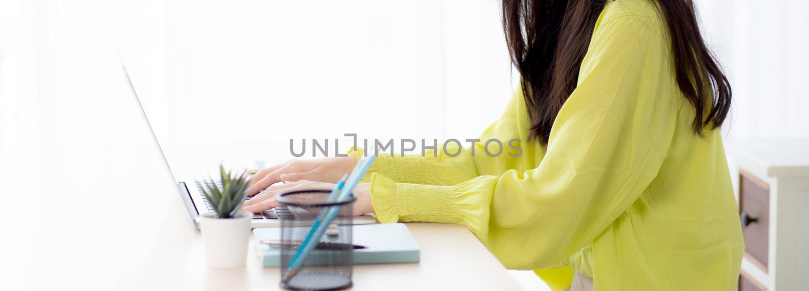 Young asian businesswoman working on laptop computer on desk at home office, freelance looking and typing on notebook on table, lifestyle of woman studying online, business and education concept.