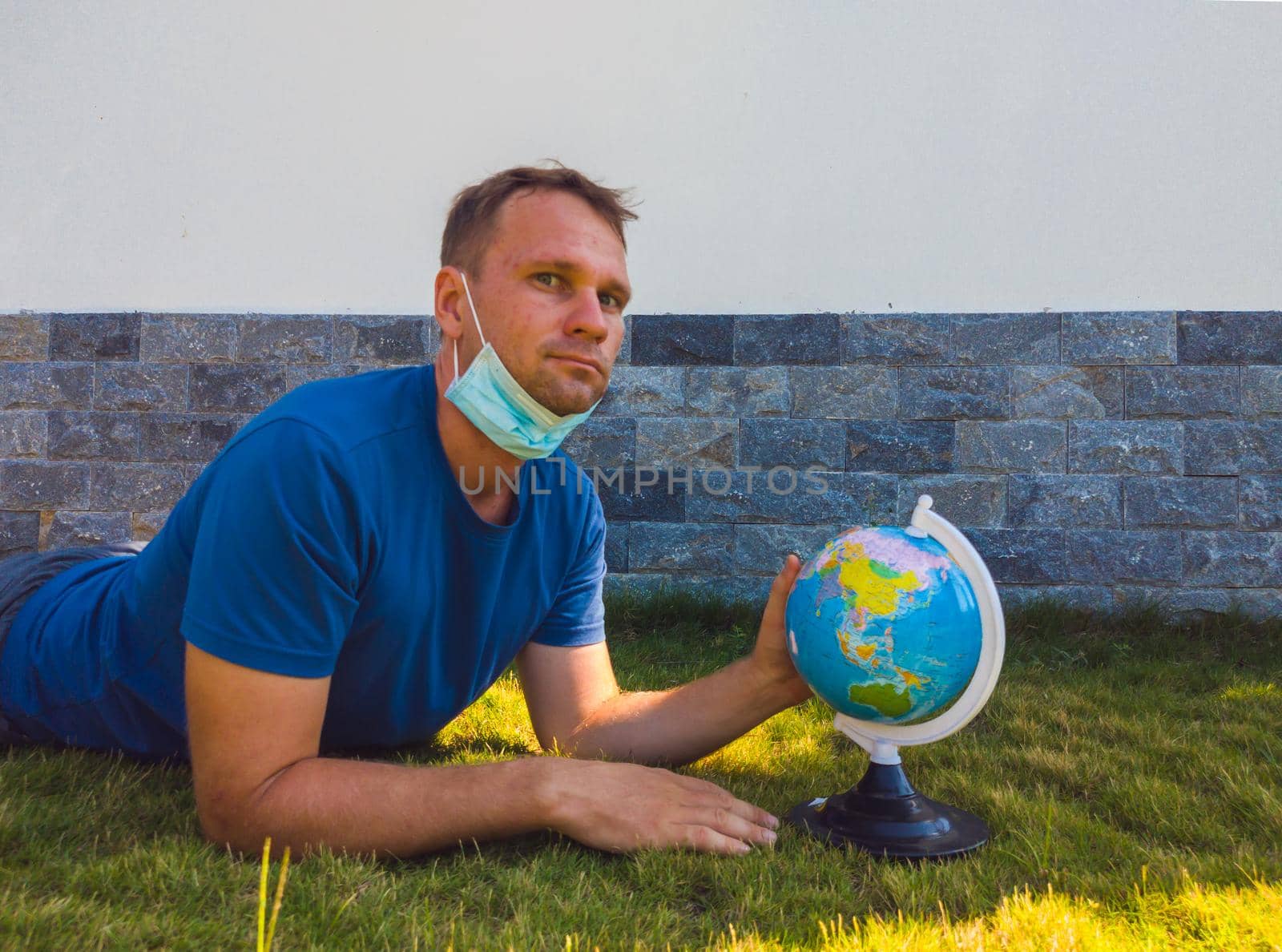 Man wearing Face Mask holding the Earth globe world map in hand. Quarantine yourself to protect spread virus. When can travel again. Epidemic pandemic coronavirus 2019-ncov sars covid-19 virus