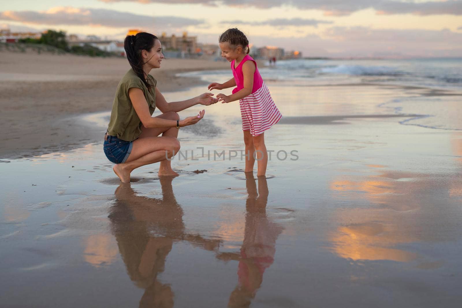Happy family. Young happy beautiful mother and her daughter having fun on the beach at sunset. Positive human emotions, feelings by Alexxoma