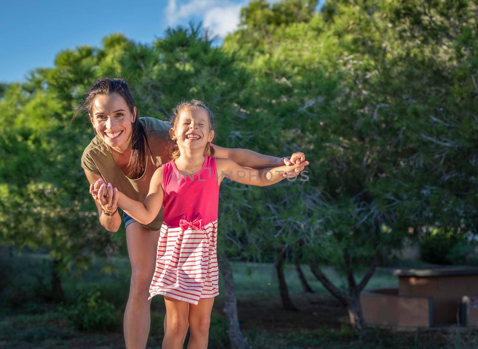 Beautiful mother and her little daughter outdoors. Beauty Mum and her Child playing in Park together at sunset. Outdoor Portrait of happy family. Mother's Day by Alexxoma