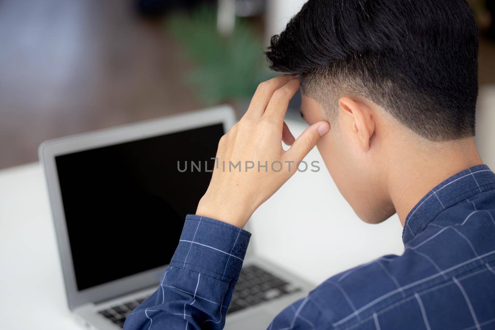 Young asian business man headache during working on laptop computer display blank screen with deadline at home, businessman with failure exhausted, stress and worried, frustrated and unsuccessful. by nnudoo