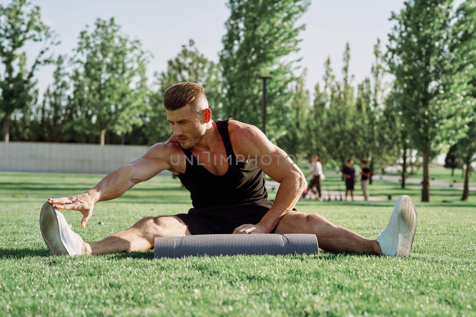 sporty man sitting on the lawn in the park training. High quality photo