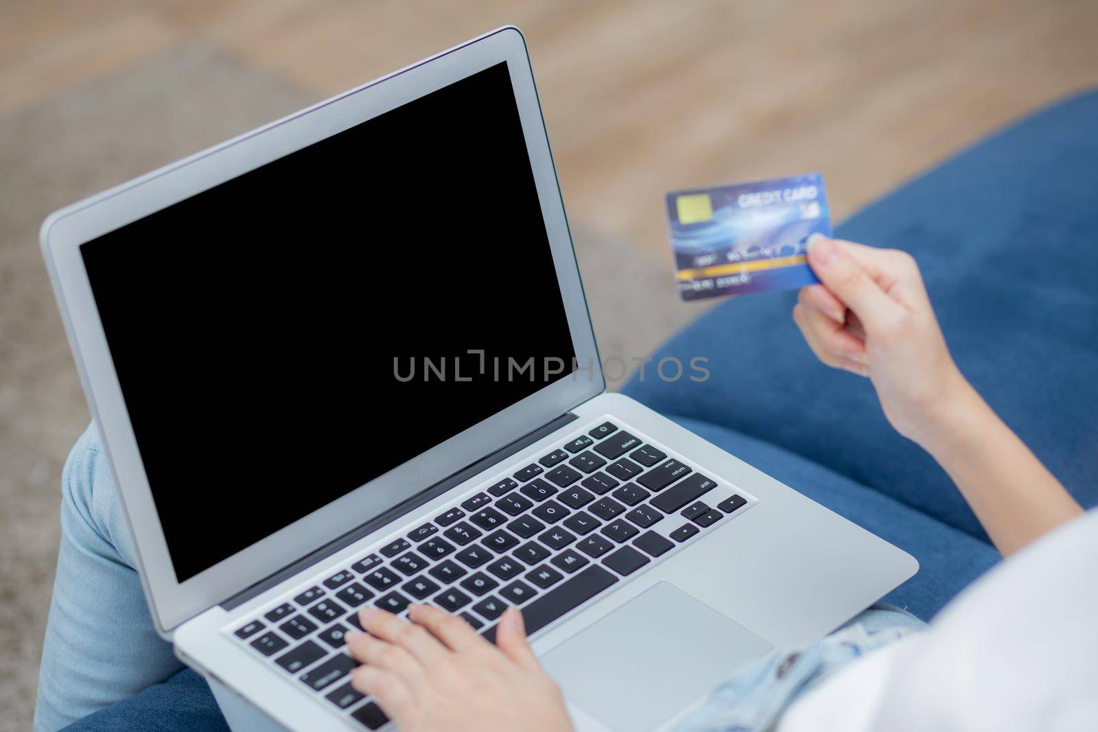 Young asian woman using laptop computer display blank screen shopping online with credit card on sofa at home, girl purchase and payment with debit card, e-commerce and technology, lifestyle concept.