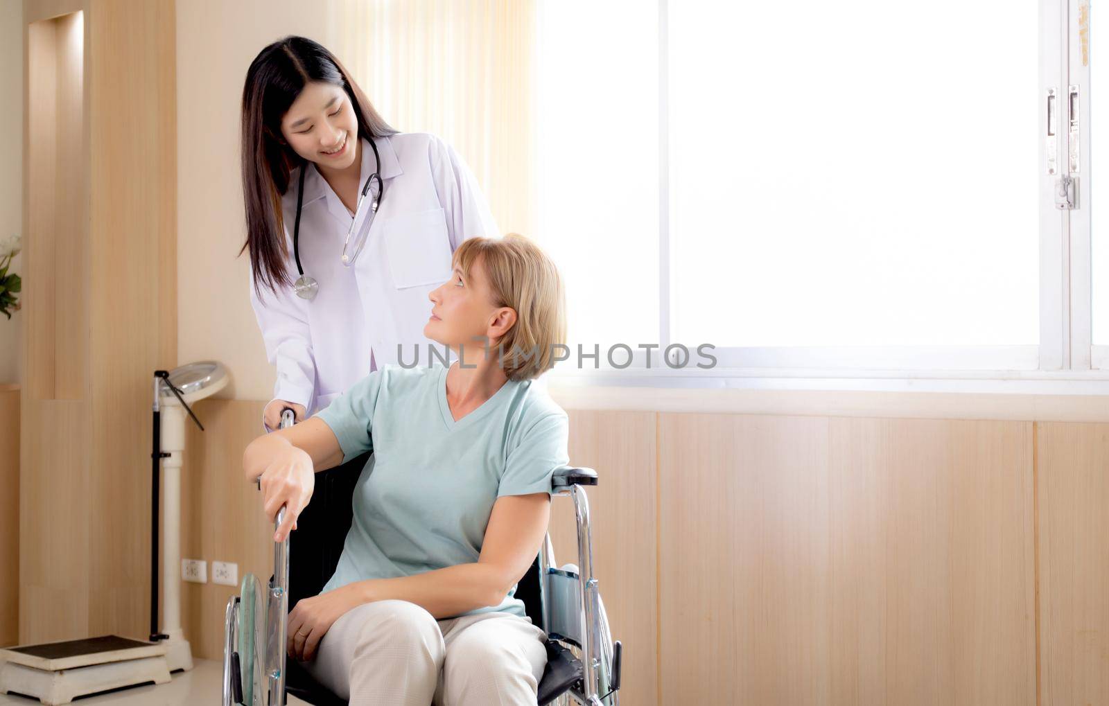 Doctor woman encourage and take care patient senior sitting wheelchair at the hospital, physician friendly with elderly, diagnostic disease and illness, health care, indoors, medical concept.