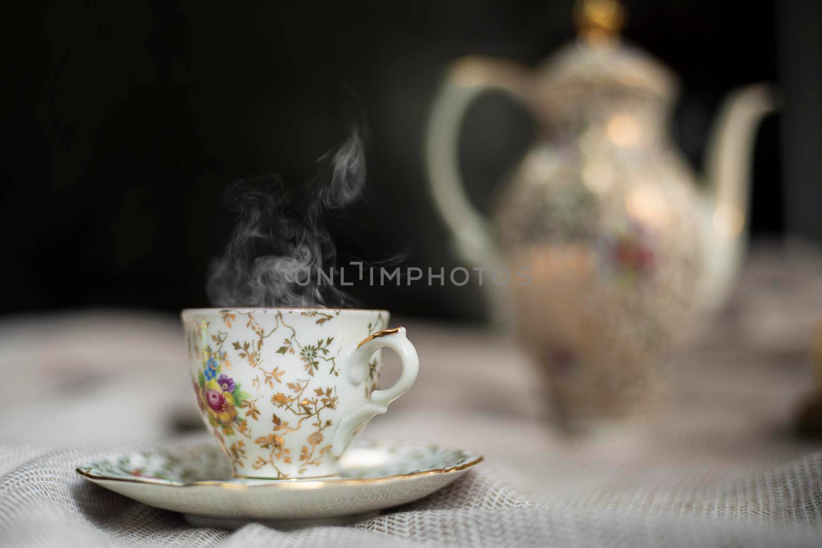 Porcelain tea pot and cup of hot tea on the table, antique traditional crockery set, high tea English afternoon tea cozy stylish interior