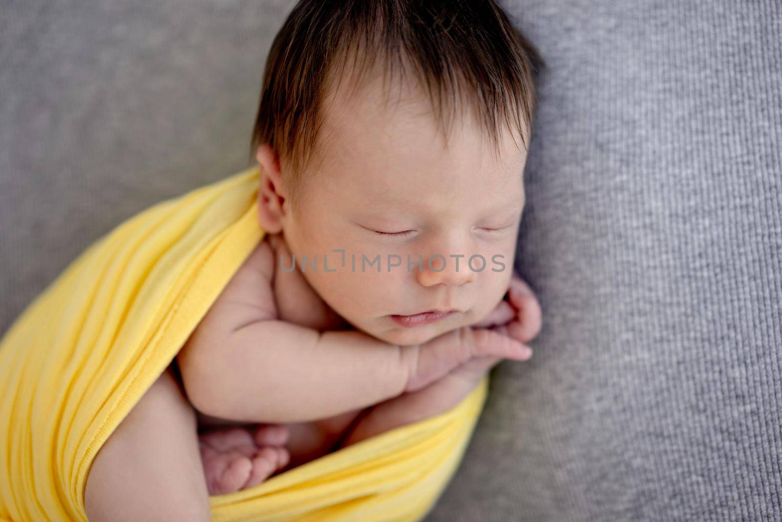 Lovely newborn sleeping wrapped up in yellow blanket