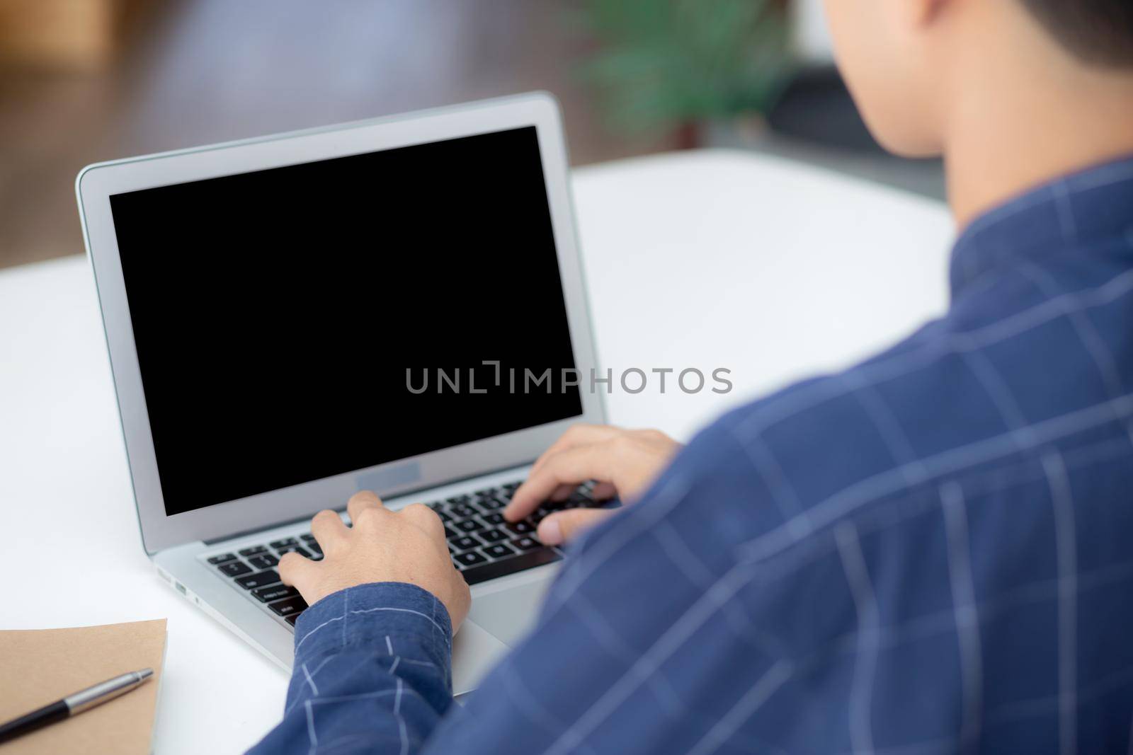 Young business man using laptop computer blank screen on desk at home, businessman work on notebook to internet online copy space for your text message, male typing keyboard, communication concept. by nnudoo
