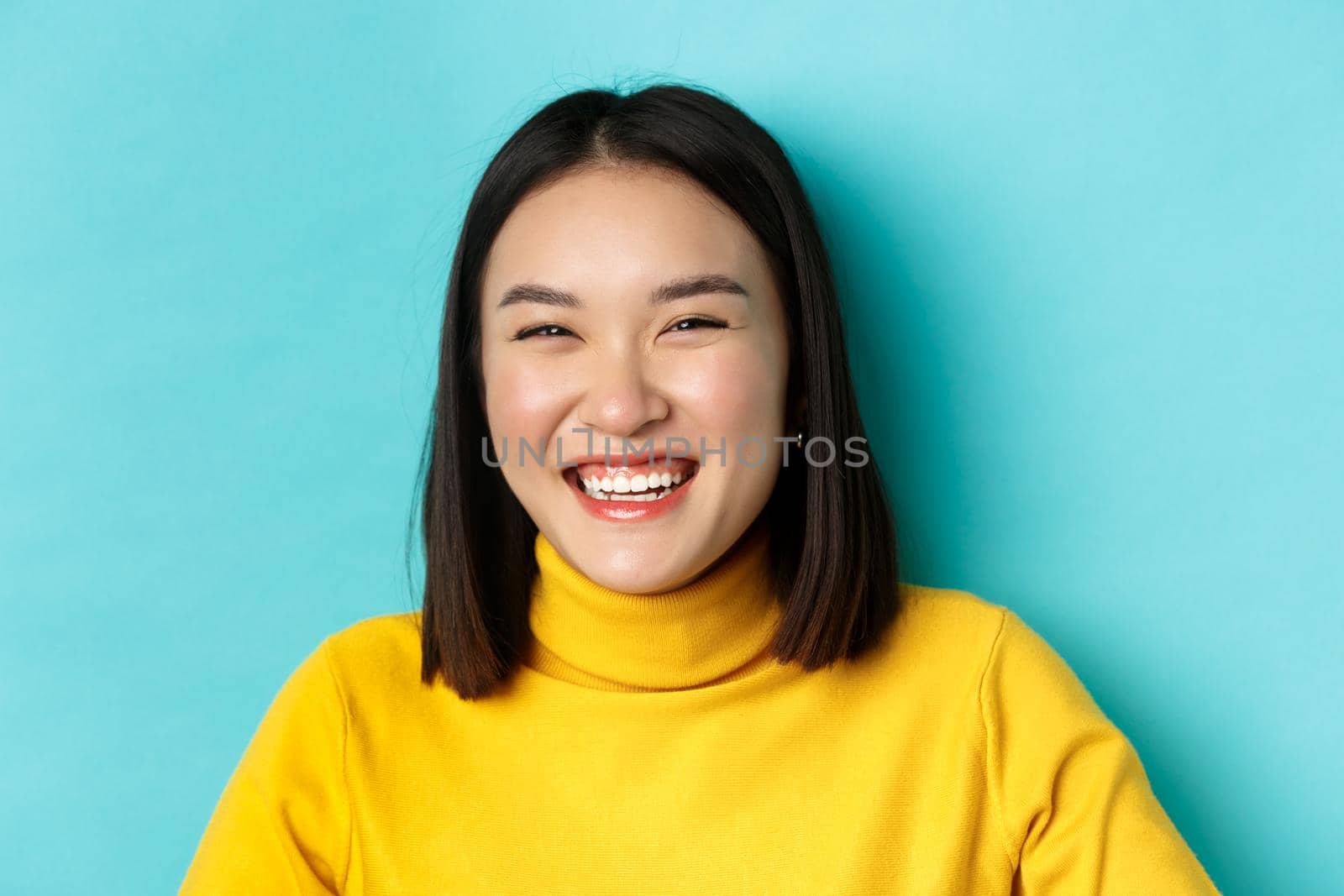 Beauty and makeup concept. Close up of carefree teenage girl smiling and laughing sincere, having fun, standing over blue background.