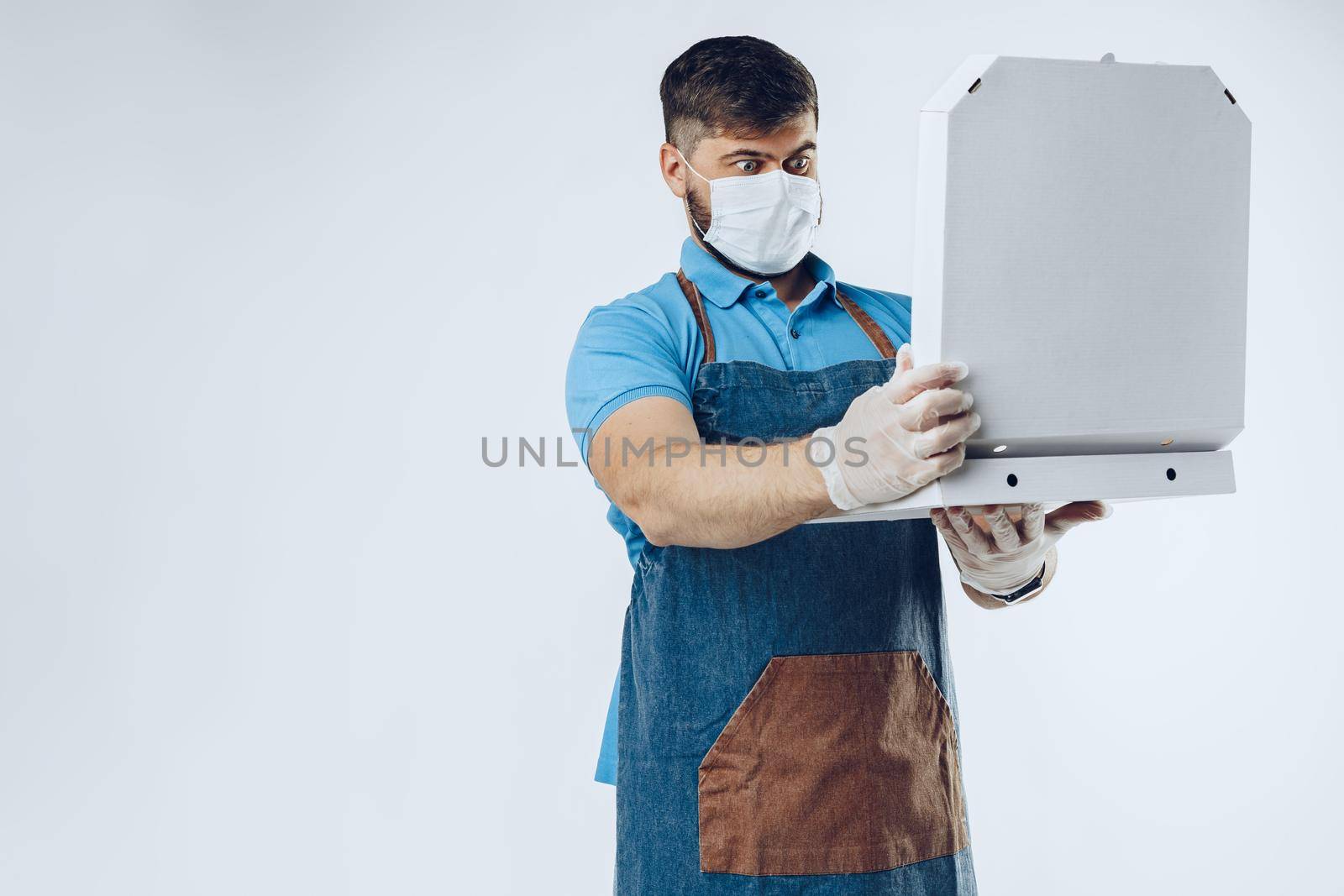 Pizza delivery man in medical gloves and mask against grey background. Safe service while coronavirus covid-19 outbreak