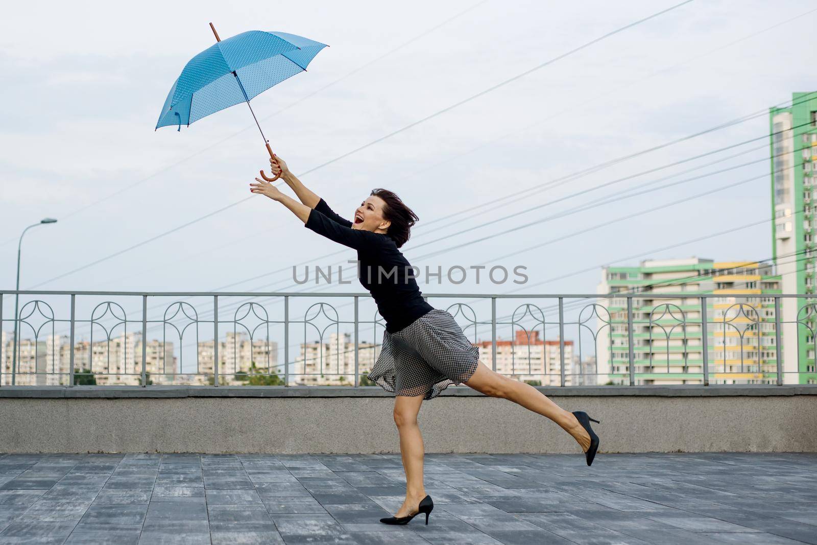 Female runs behind an umbrella against the backdrop of the city