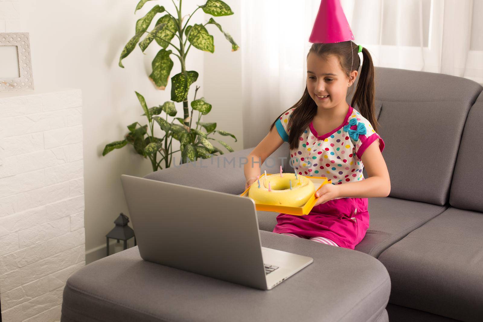 Children virtual birthday party with cake online together with her friend in video conference. With digital telephone for a online meeting. Girl celebrating birthday online in quarantine time by Andelov13