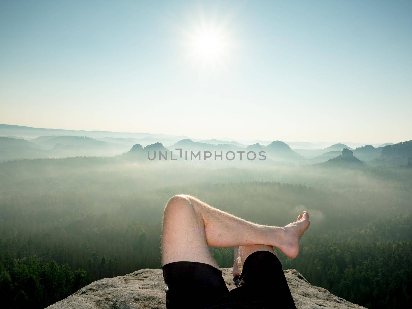Crossed male barefoot legs of man relax on mountain summit.  by rdonar2