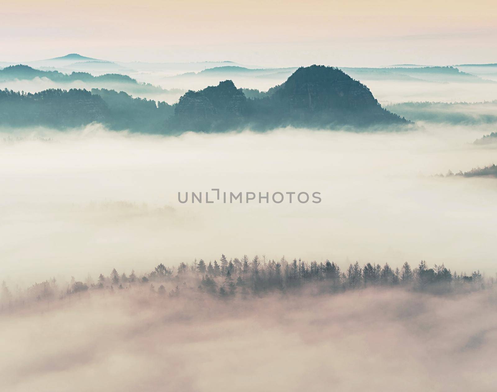 Landscape misty panorama. Fantastic dreamy sunrise on rocky mountains with view into misty valley below 