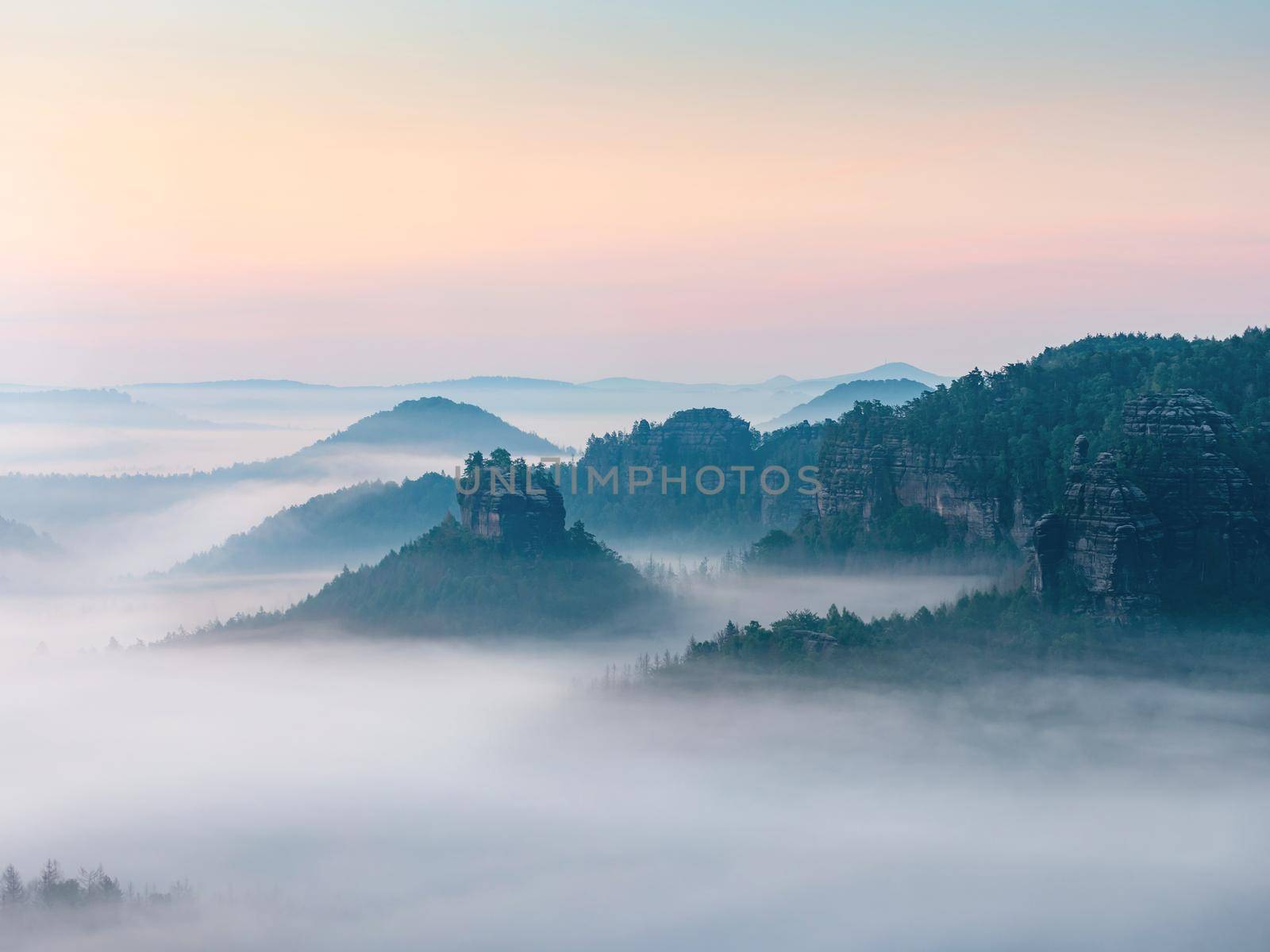 The fairy rock of Winterstein, also called Hinteres Raubschloss or Raubstein sticking out of morning mist.  It is a sandstone rock massif, the butte with rest of stronghold ruin in the Saxon Switzerland National Park.