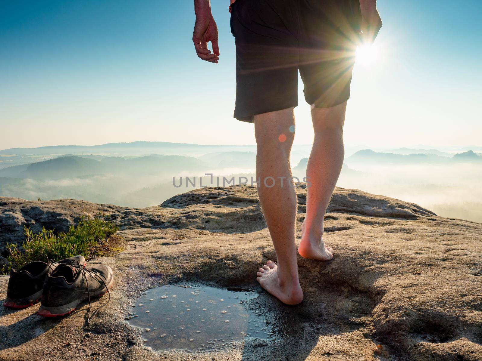Hiker next to taken off shoes and water puddle on sandstone rock edge enjoy  view by rdonar2