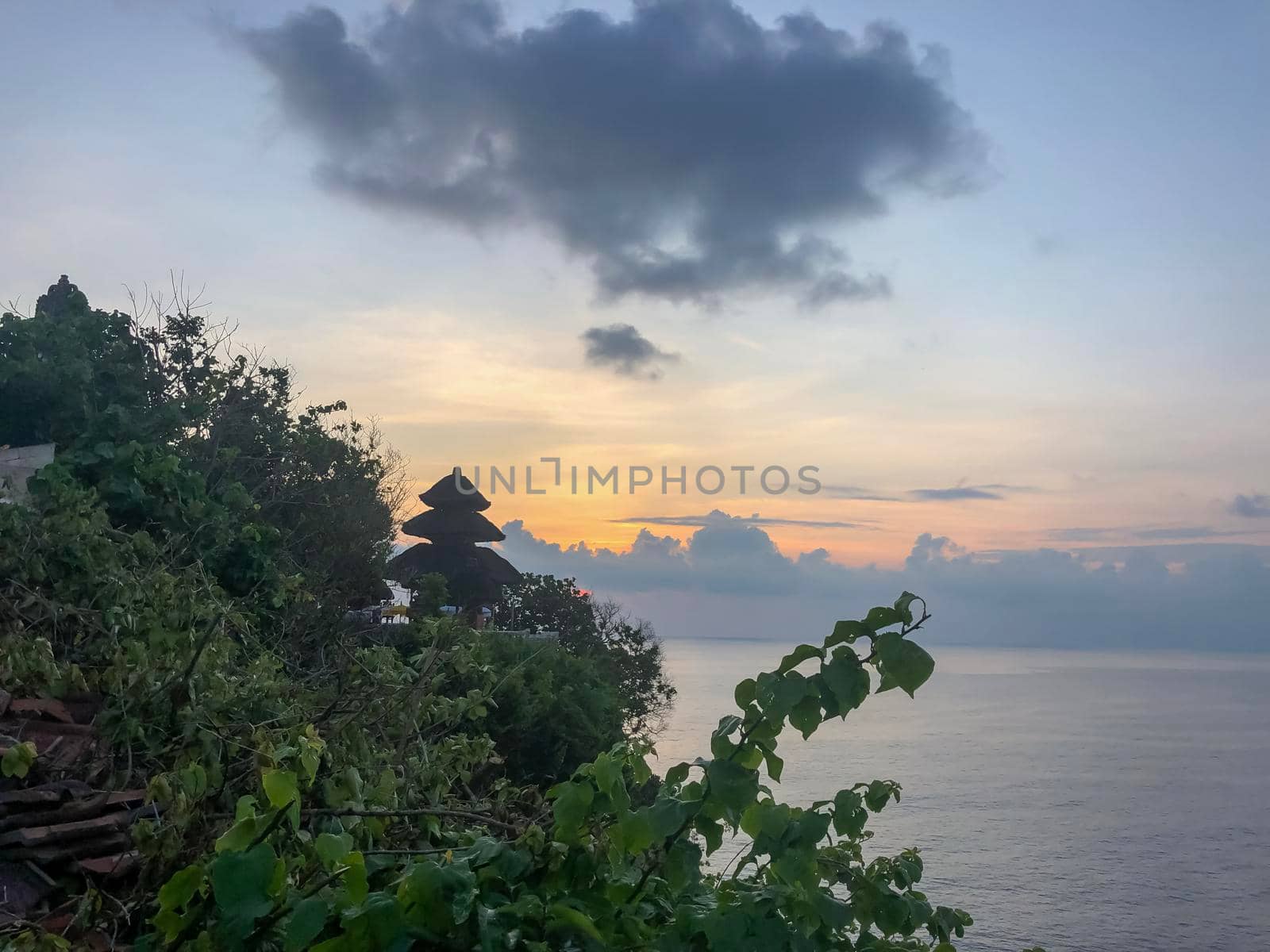 A scenic Uluwatu cliff with pavilion and blue sea in Bali - stock photo