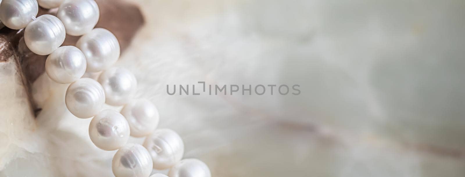 Nature white string of pearls on marble background in soft focus, with highlights.