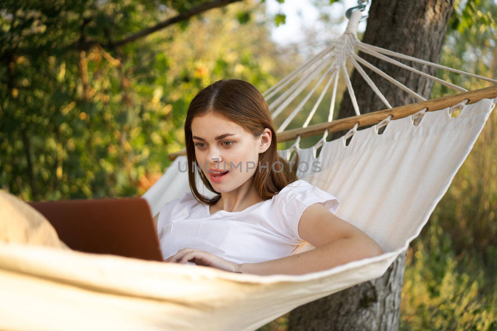 women outdoors lies in a hammock with a laptop freelance internet. High quality photo