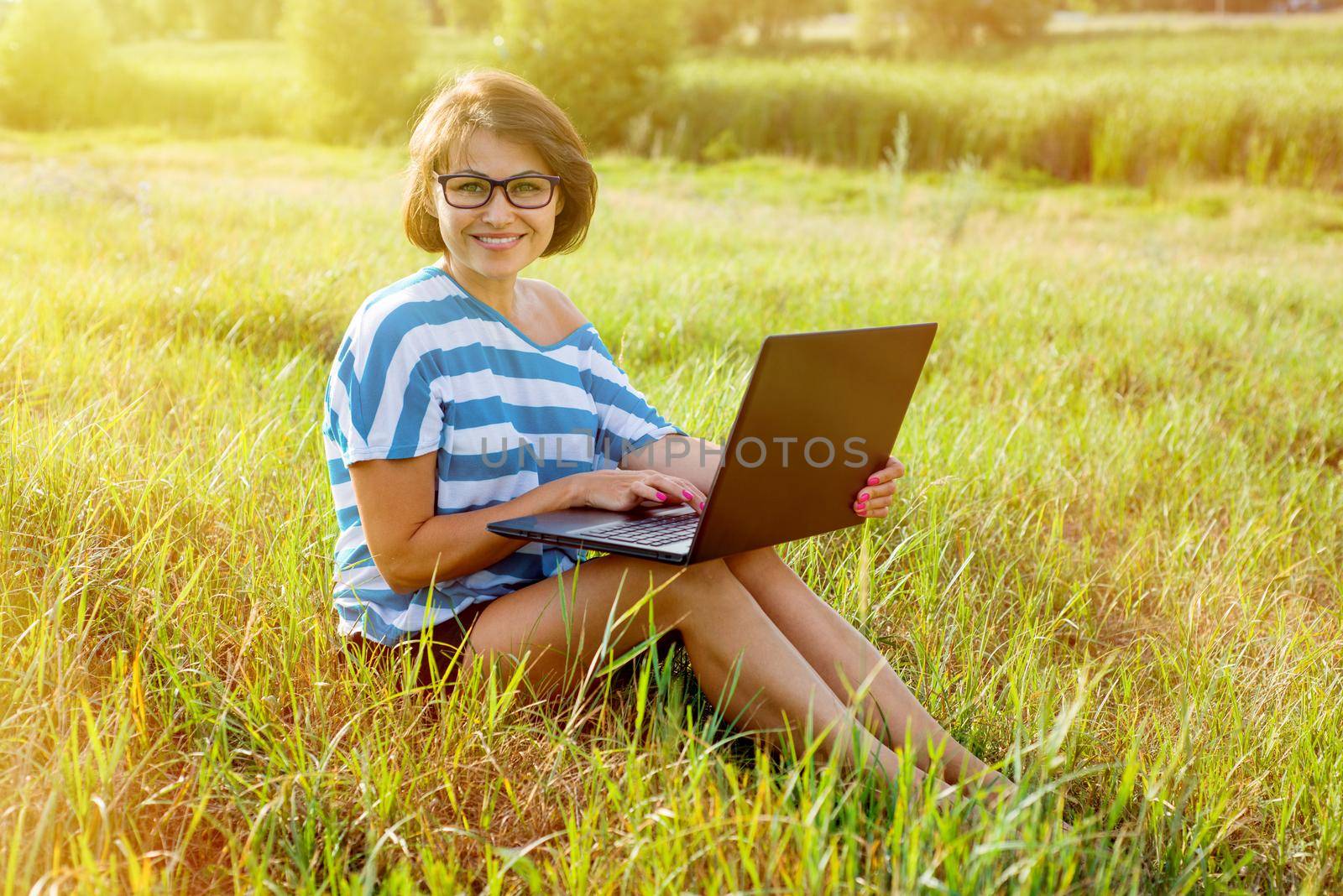 Beautiful woman with a laptop. Smiling at the camera. The picture was taken in the park.