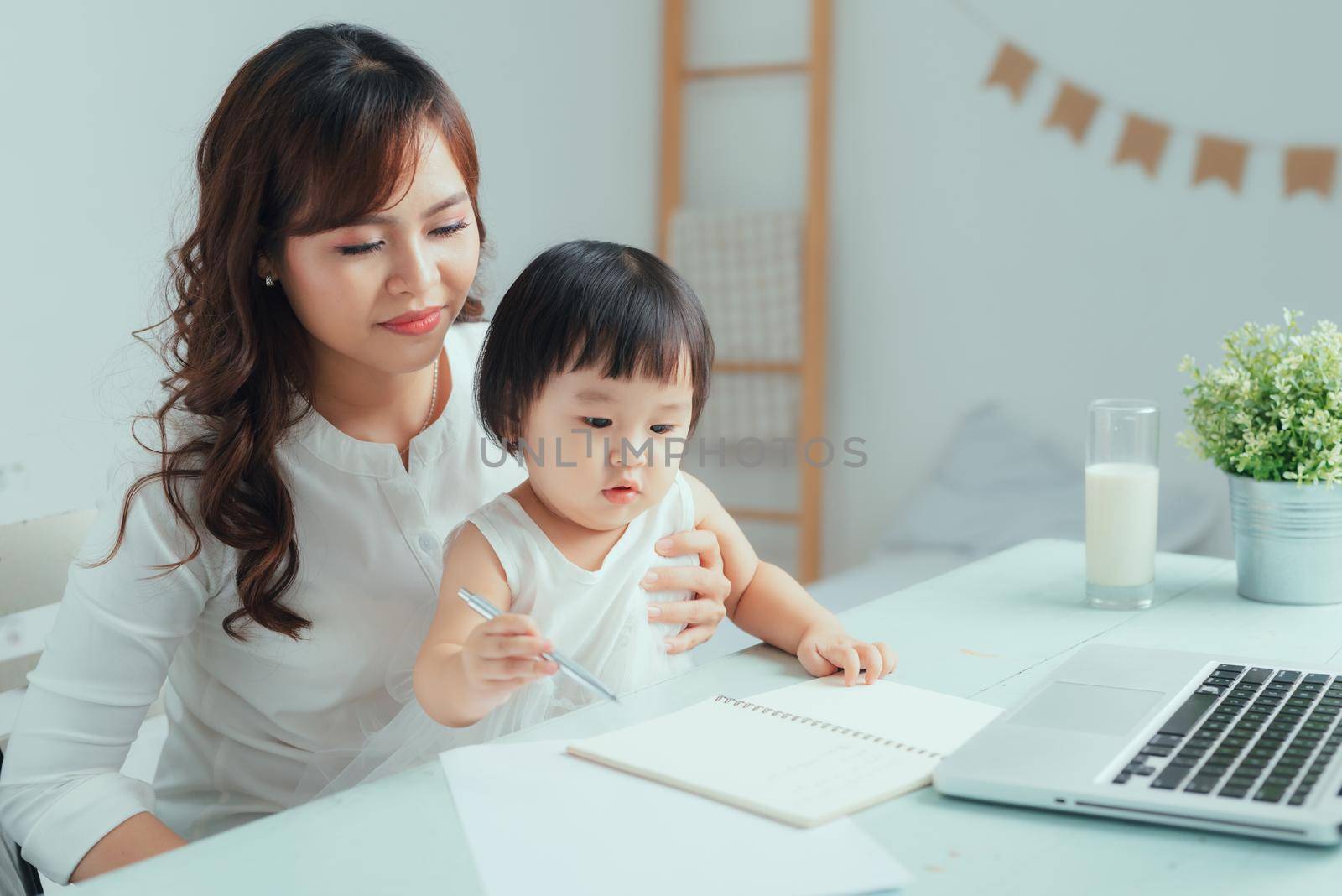 Stay at home mom working remotely on laptop while taking care of her baby.