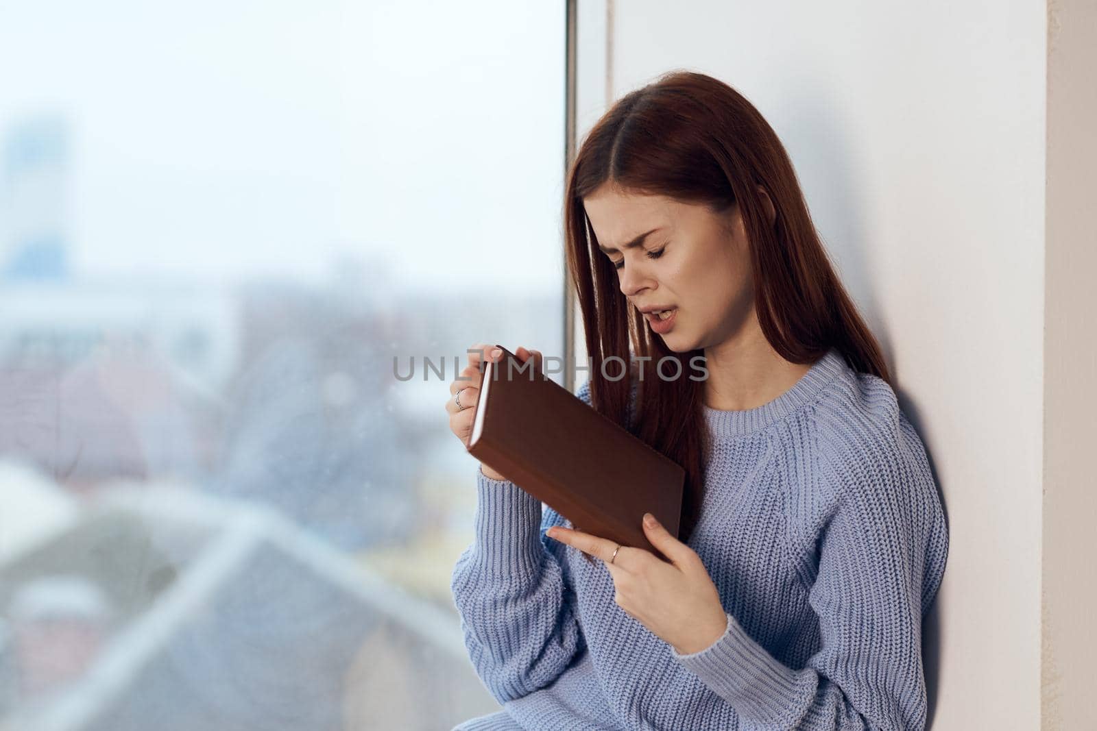 woman reading a book near the window with a cup of drink rest. High quality photo