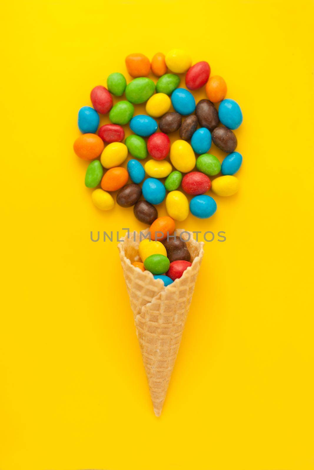 splash of colorful nuts or candies from ice cone. Explosion of dates close up on yellow background. Creative concept of proper snacks