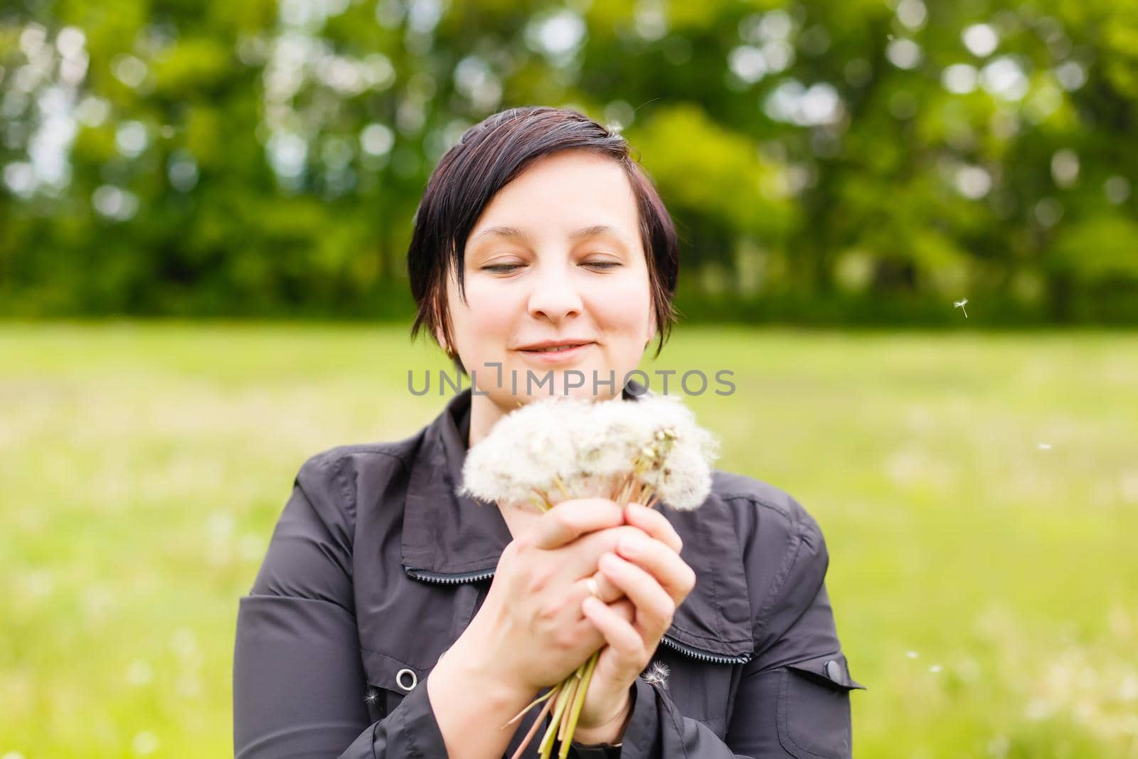 Girl blowing on white dandelion in the forest