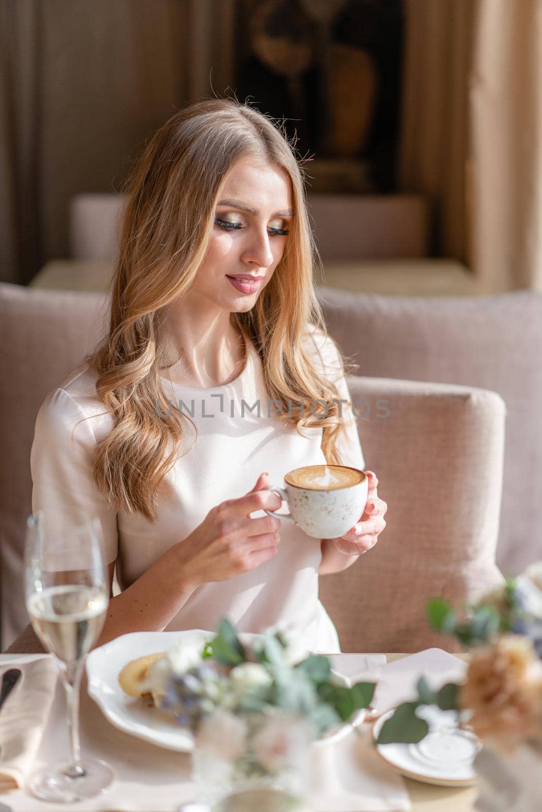 Portrait of a beautiful young elegant blonde woman in the cafe with a glass of champagne