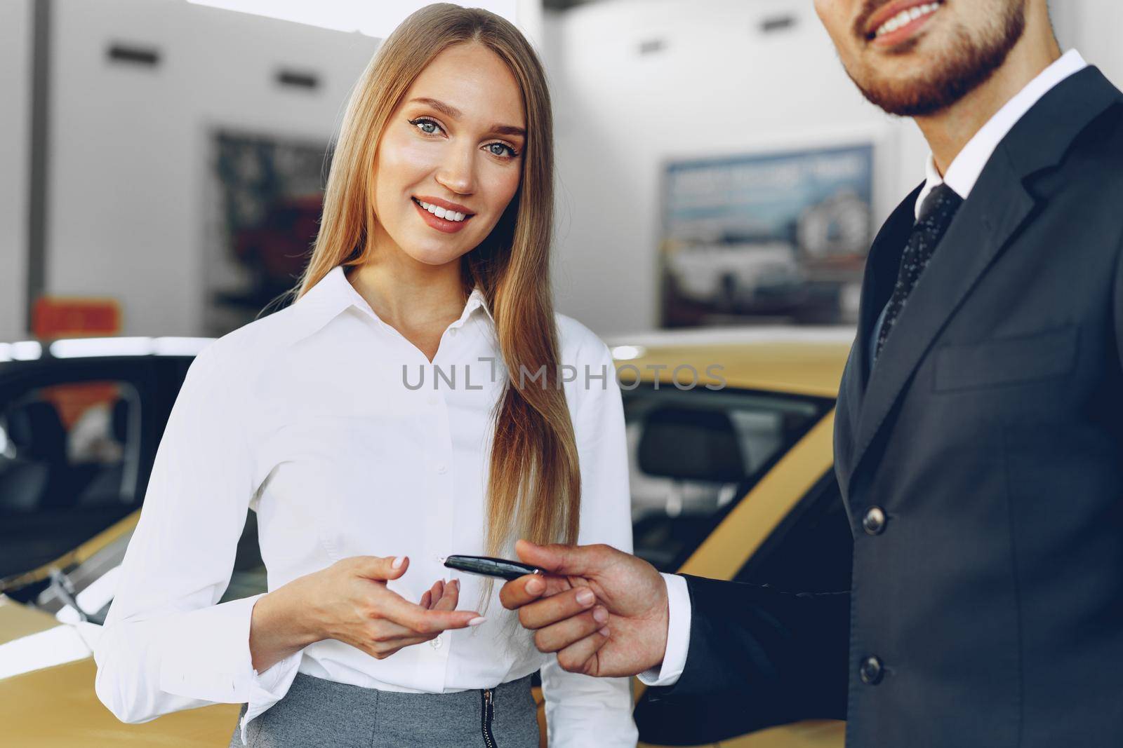 Young attractive woman buying a new car in car salon by Fabrikasimf