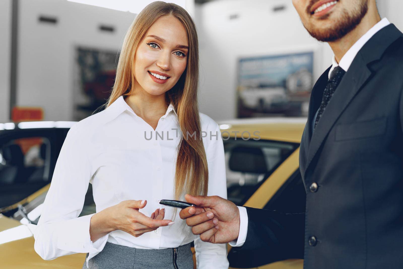 Young attractive woman buying a new car in car salon close up