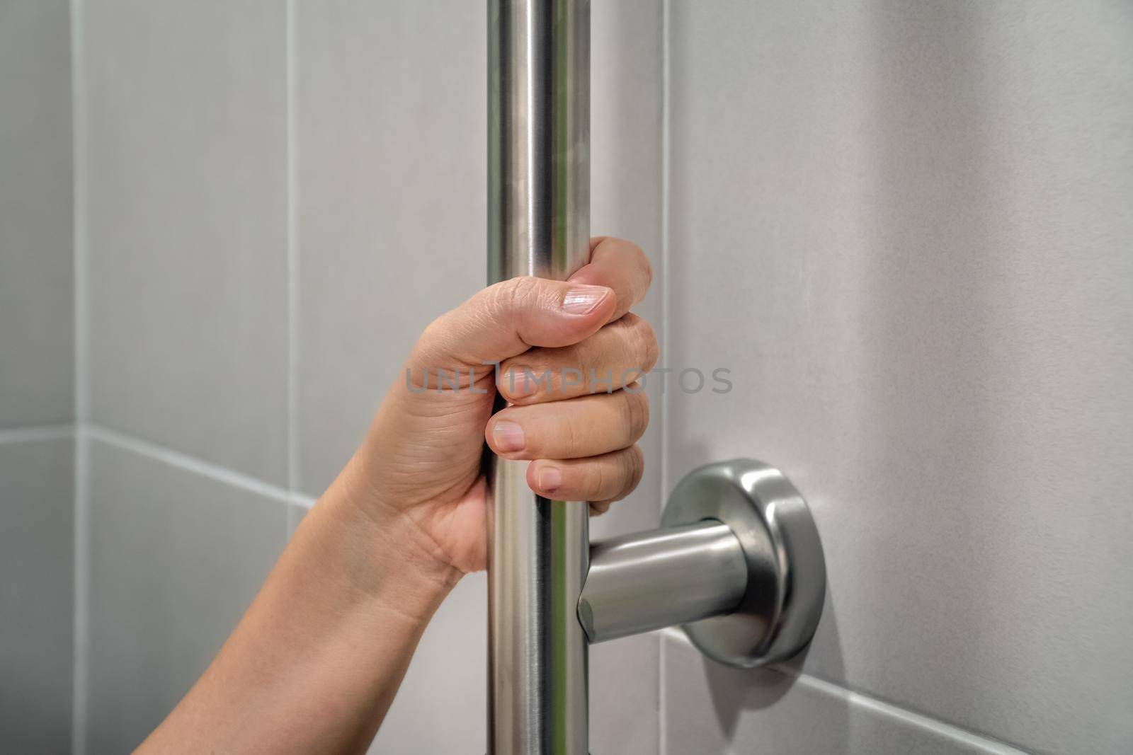 Woman holding on handrail in toilet. by toa55