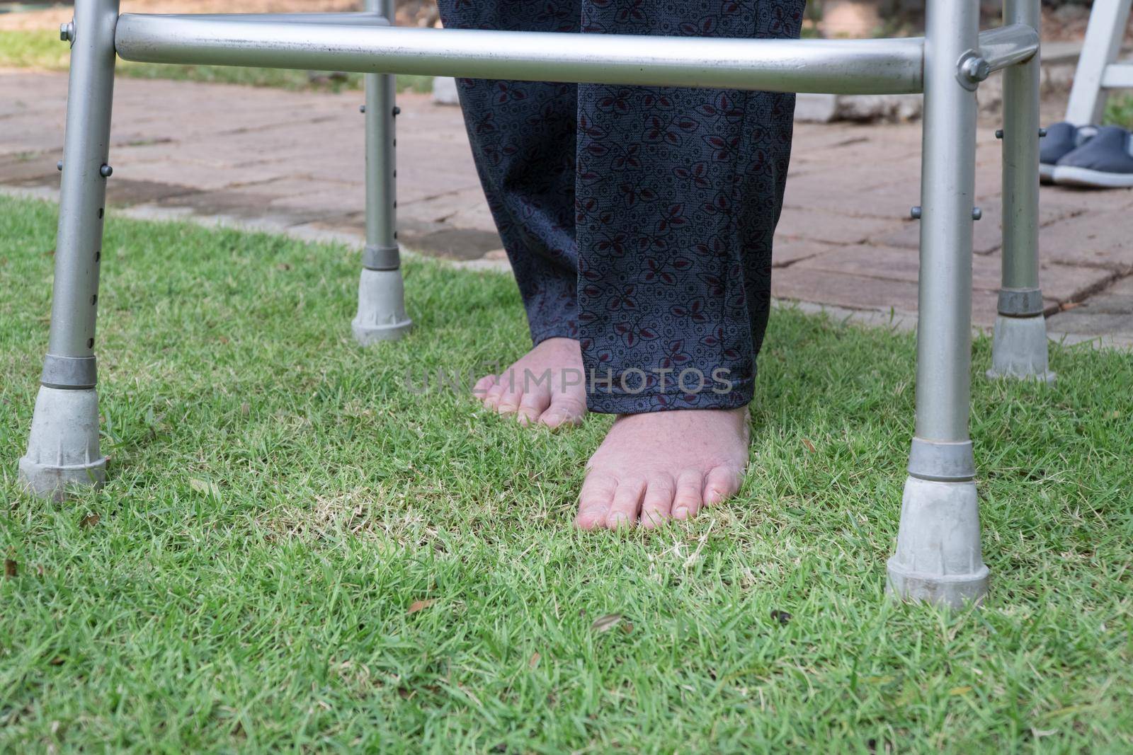 Elderly woman walking barefoot therapy on grass in backyard. by toa55