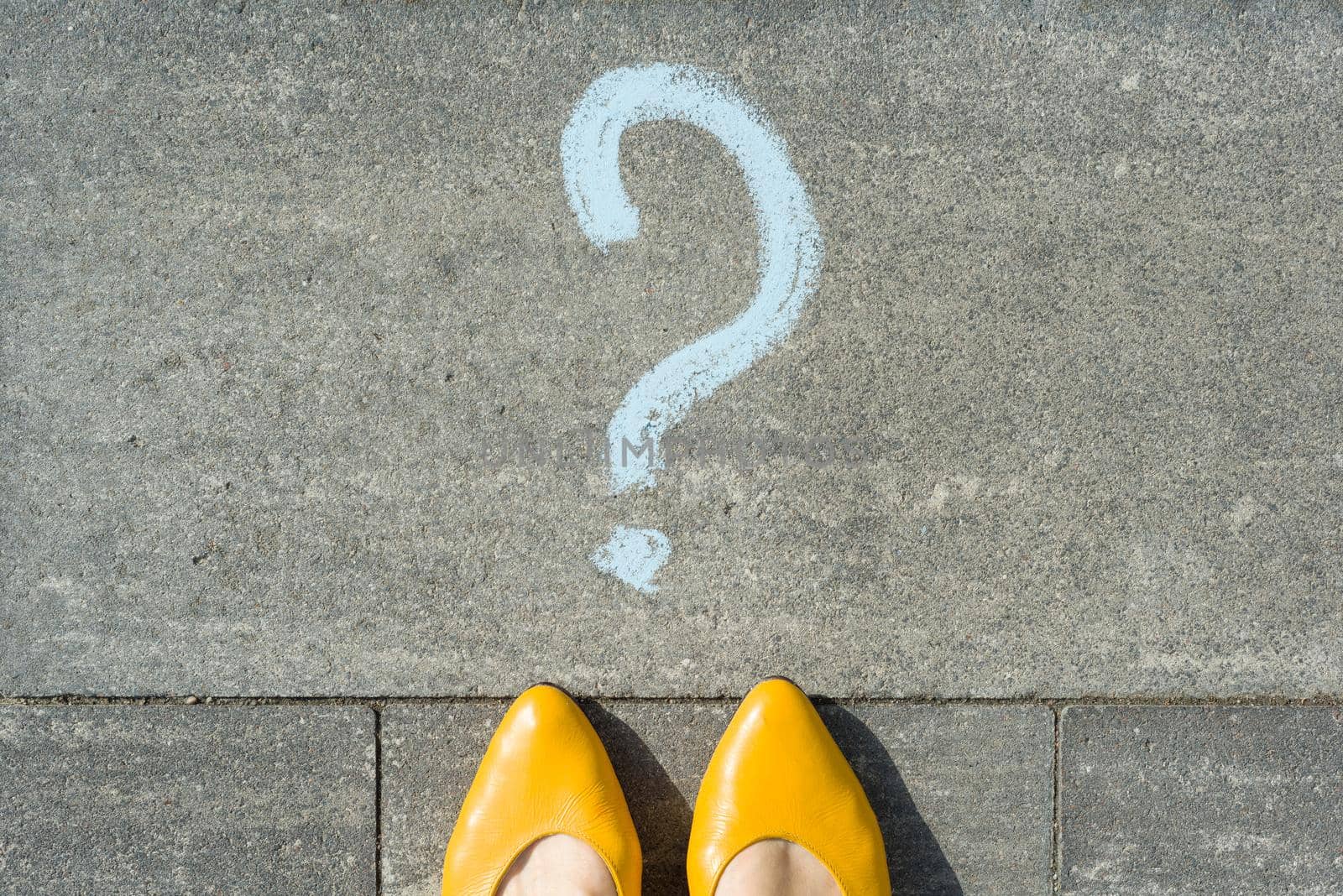 Woman feet with question mark in front of her legs painted on the asphalt