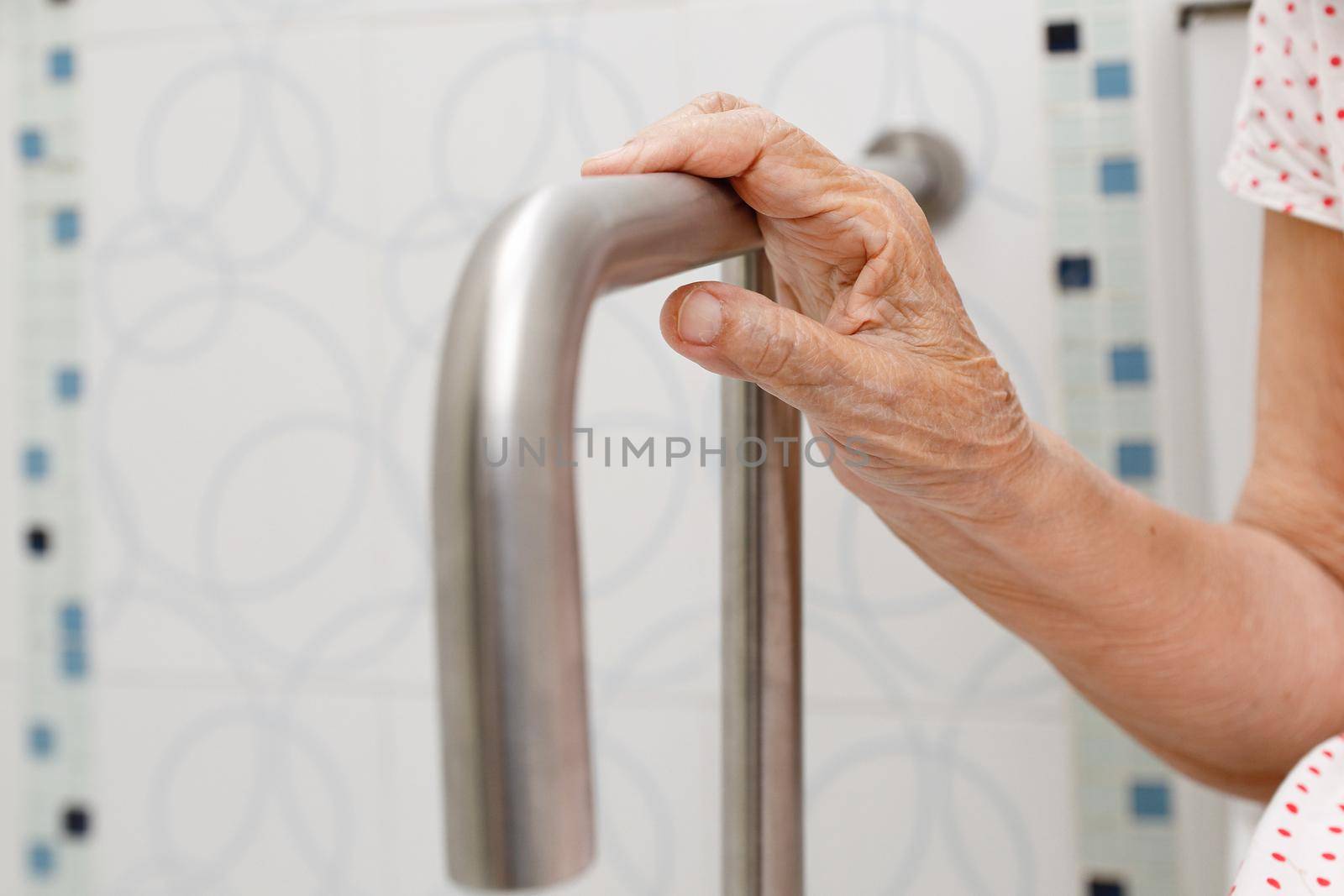 Elderly woman holding on handrail in toilet.