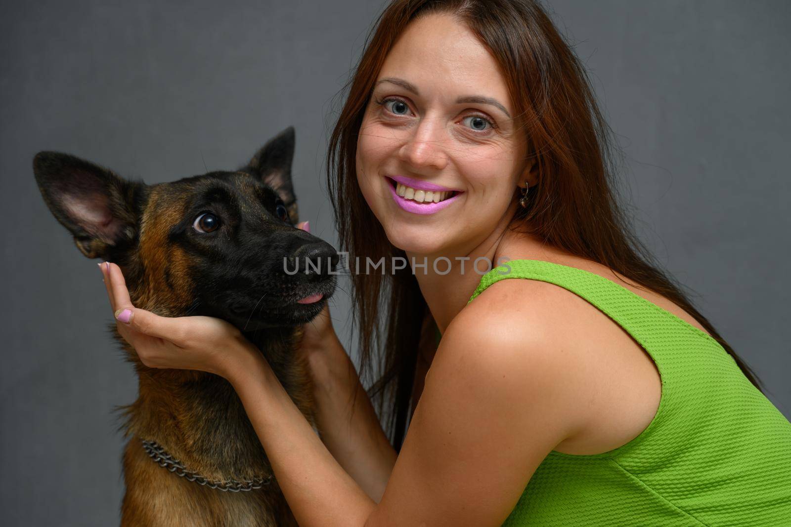 Portrait of a young woman posing playing with a Belgian shepherd dog in the studio