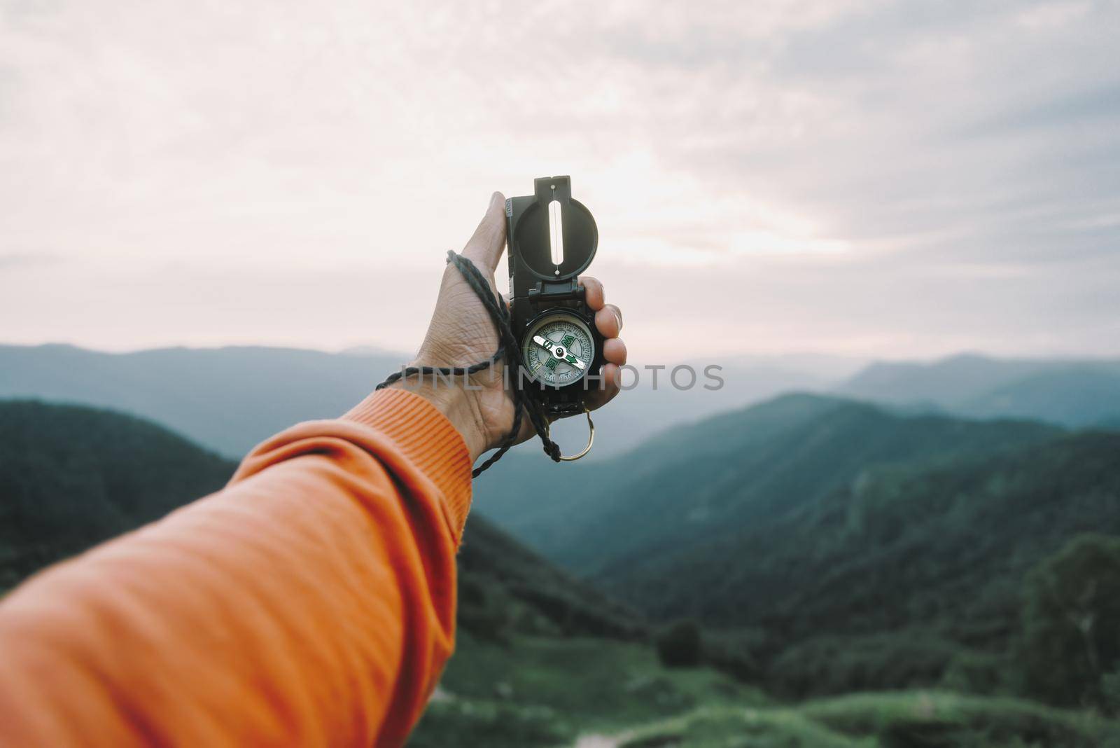 Man explorer searching direction with compass in summer mountains, point of view.