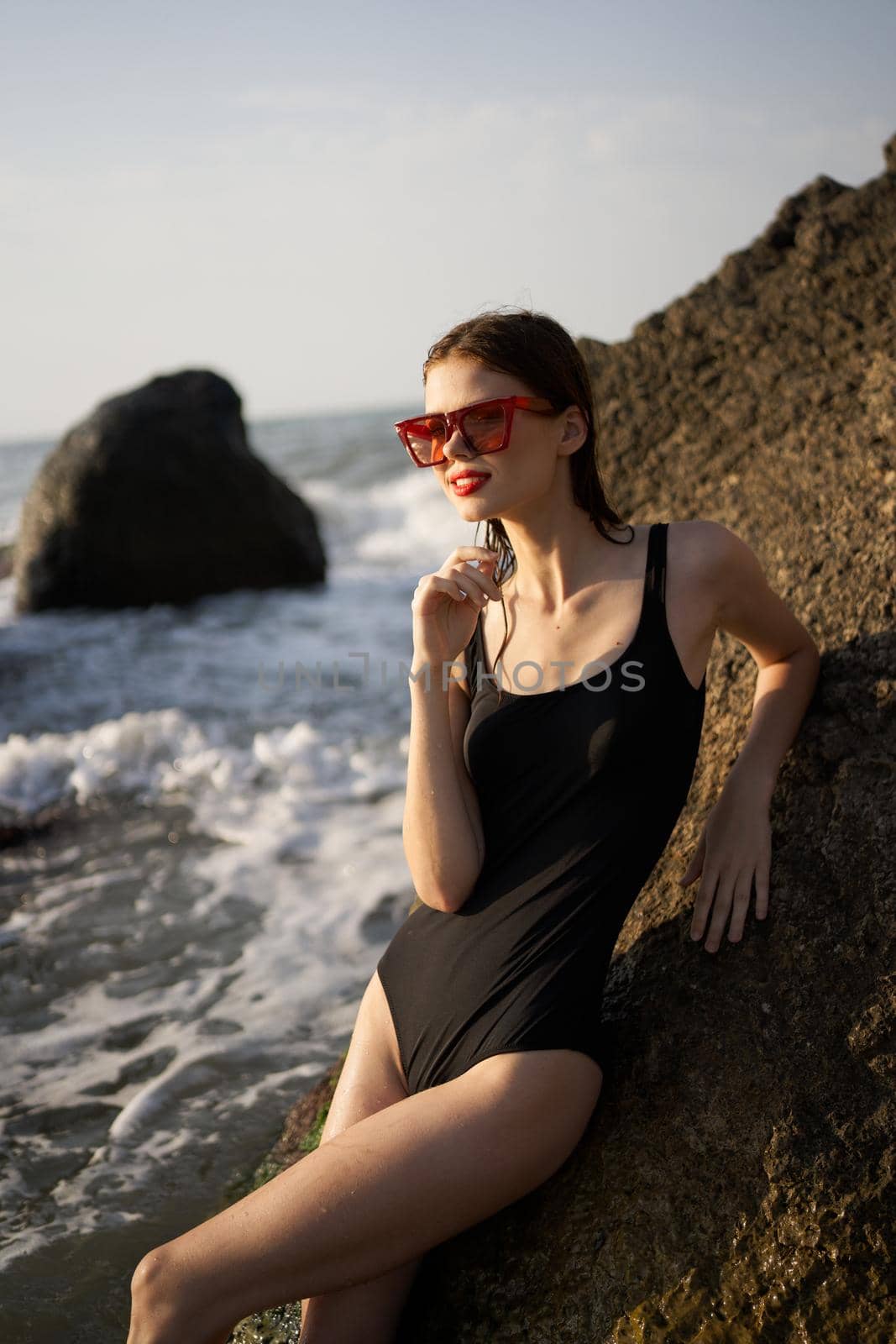 woman in swimsuit sunglasses ocean rocks posing by Vichizh