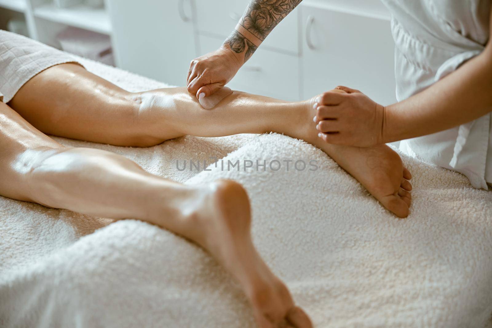 Massagist woman is doing professional leg massage in modern salon