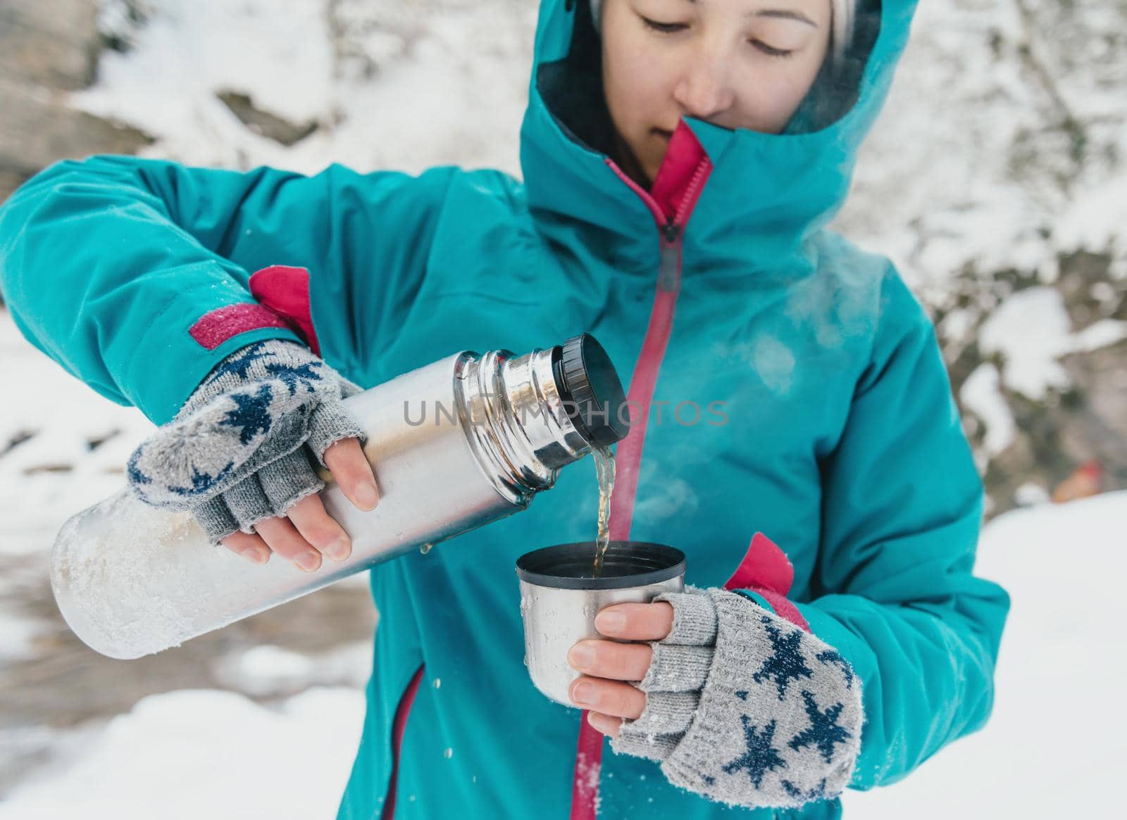 Traveler young woman pouring tea from thermos in winter outdoor