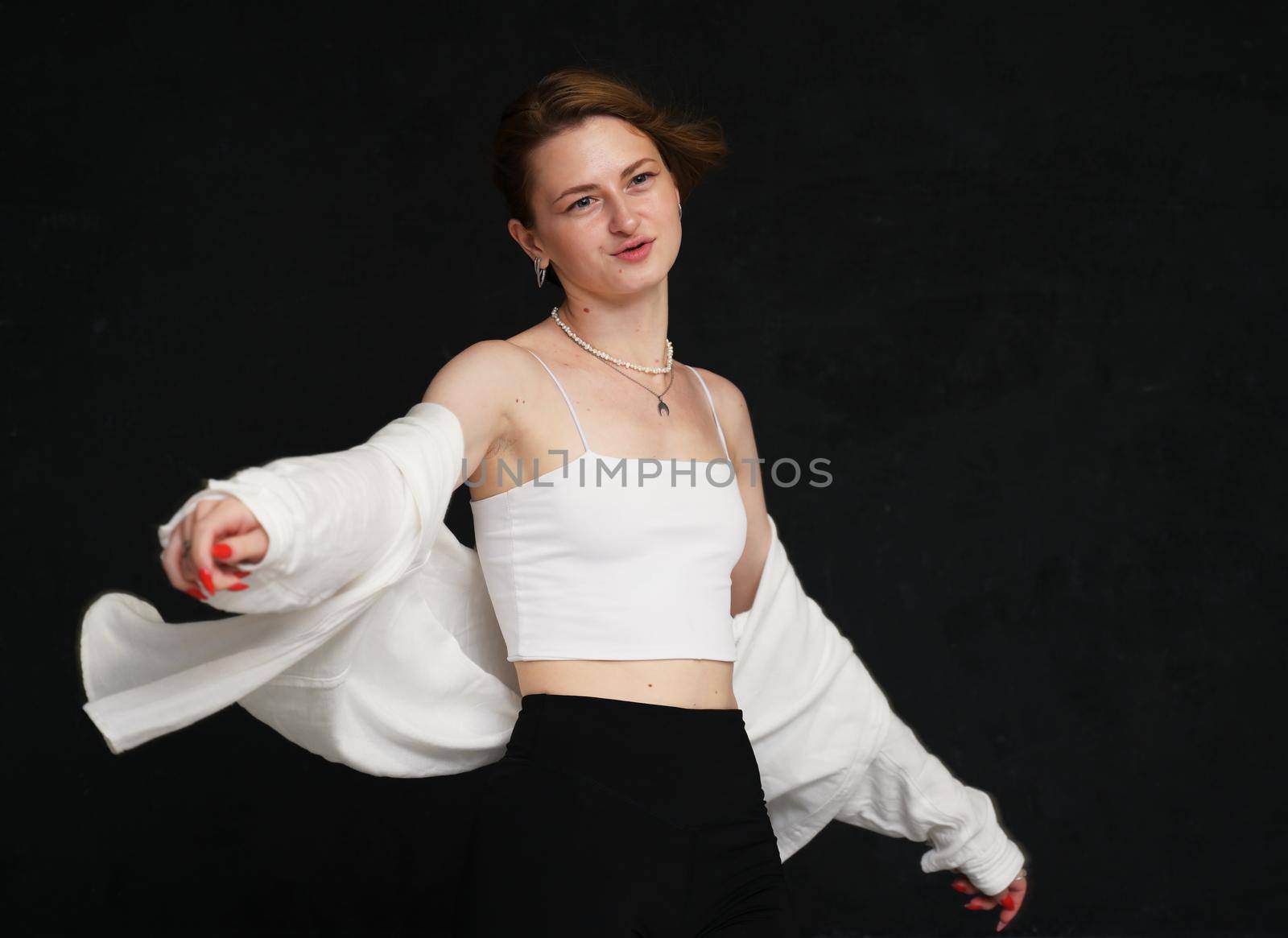 Photo caucasian girl in light clothes in the studio on a black background posing in the wind