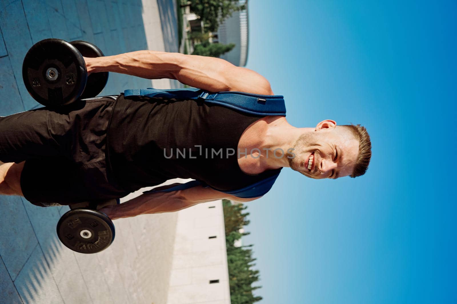athletic man with dumbbells in his hands in the park training lifestyle. High quality photo
