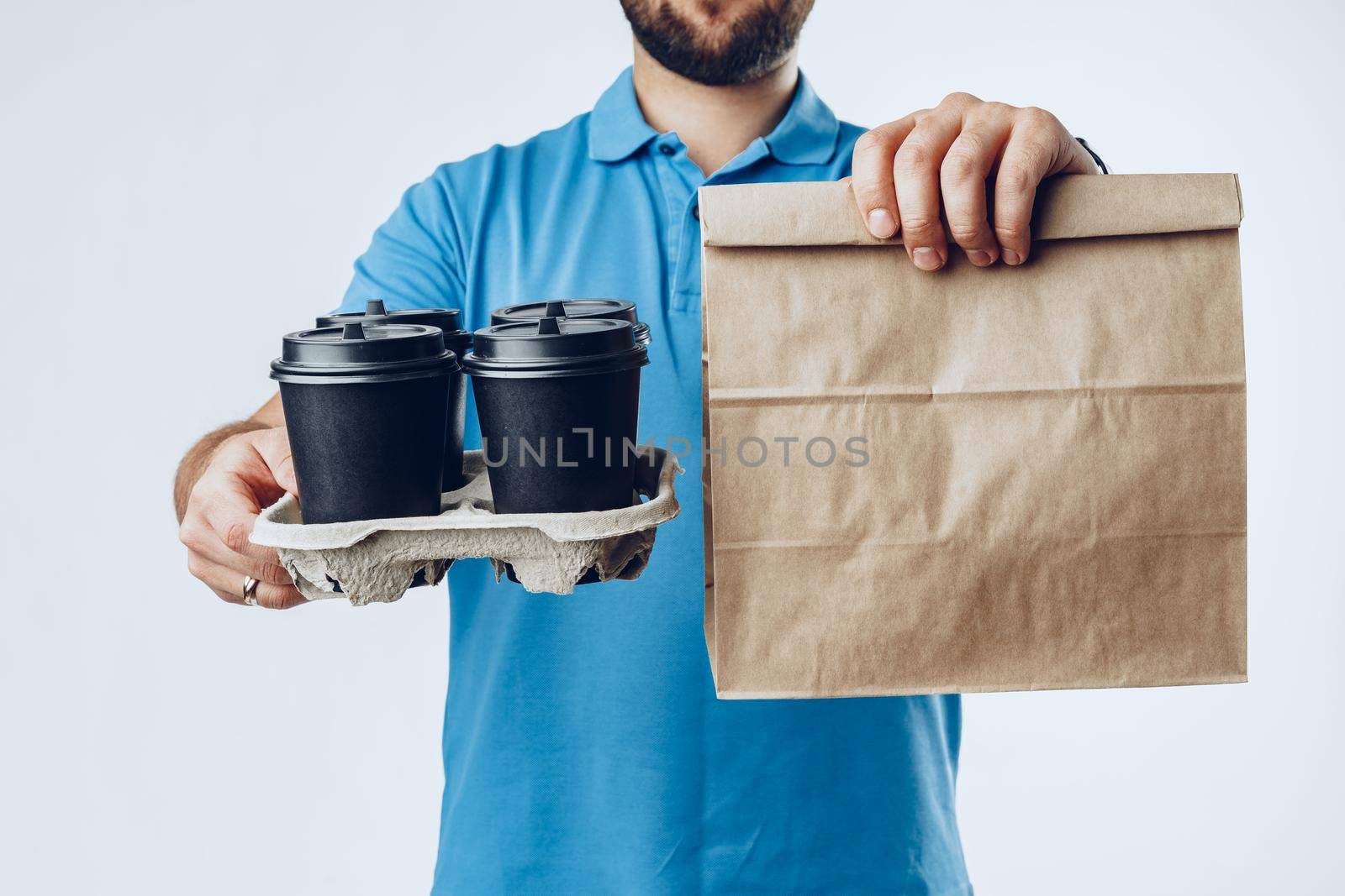 Unrecognizable man in blue polo shirt with food delivery orders against light grey background