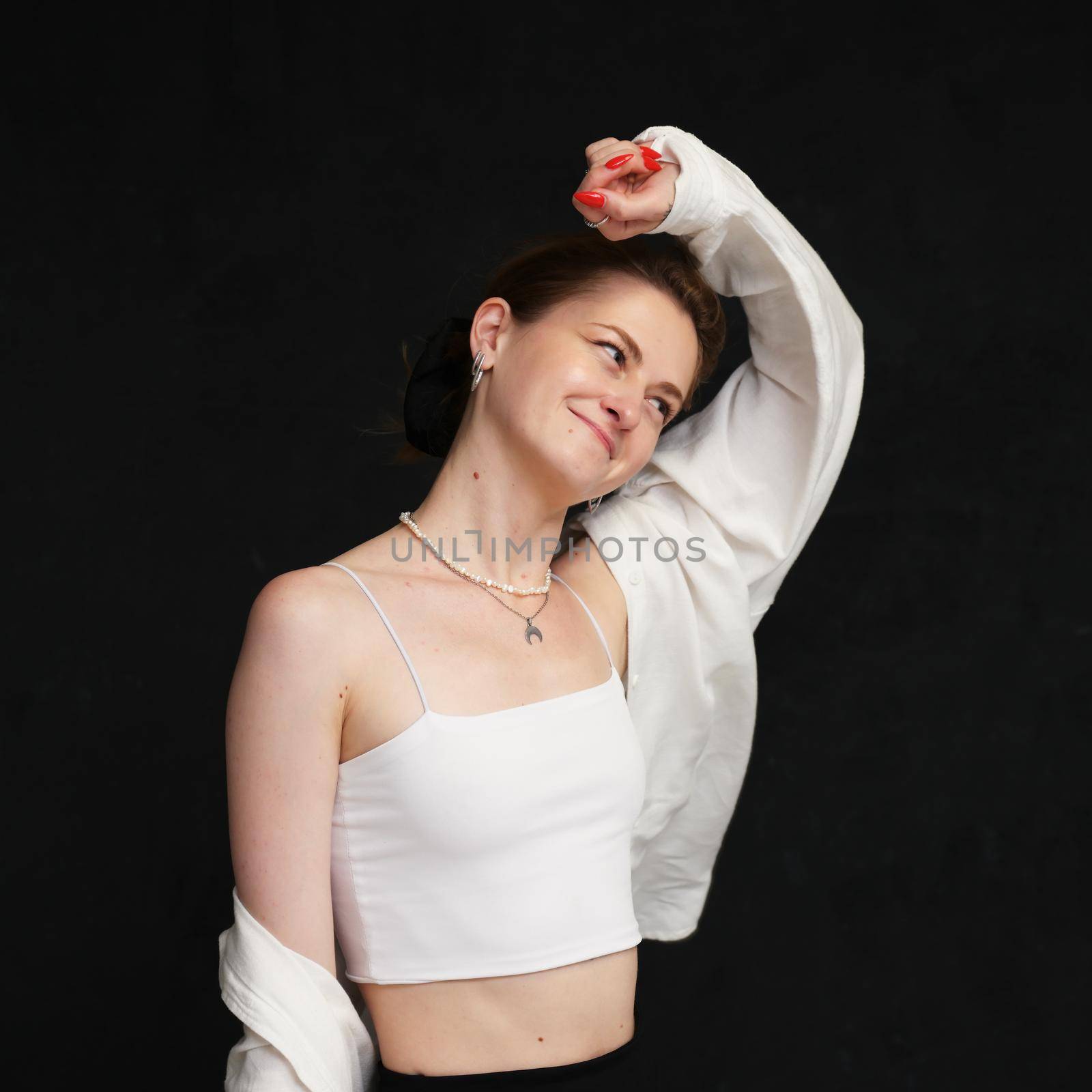 Young lovely happy girl posing looking to the side in light clothes on a black background. Universal concept.