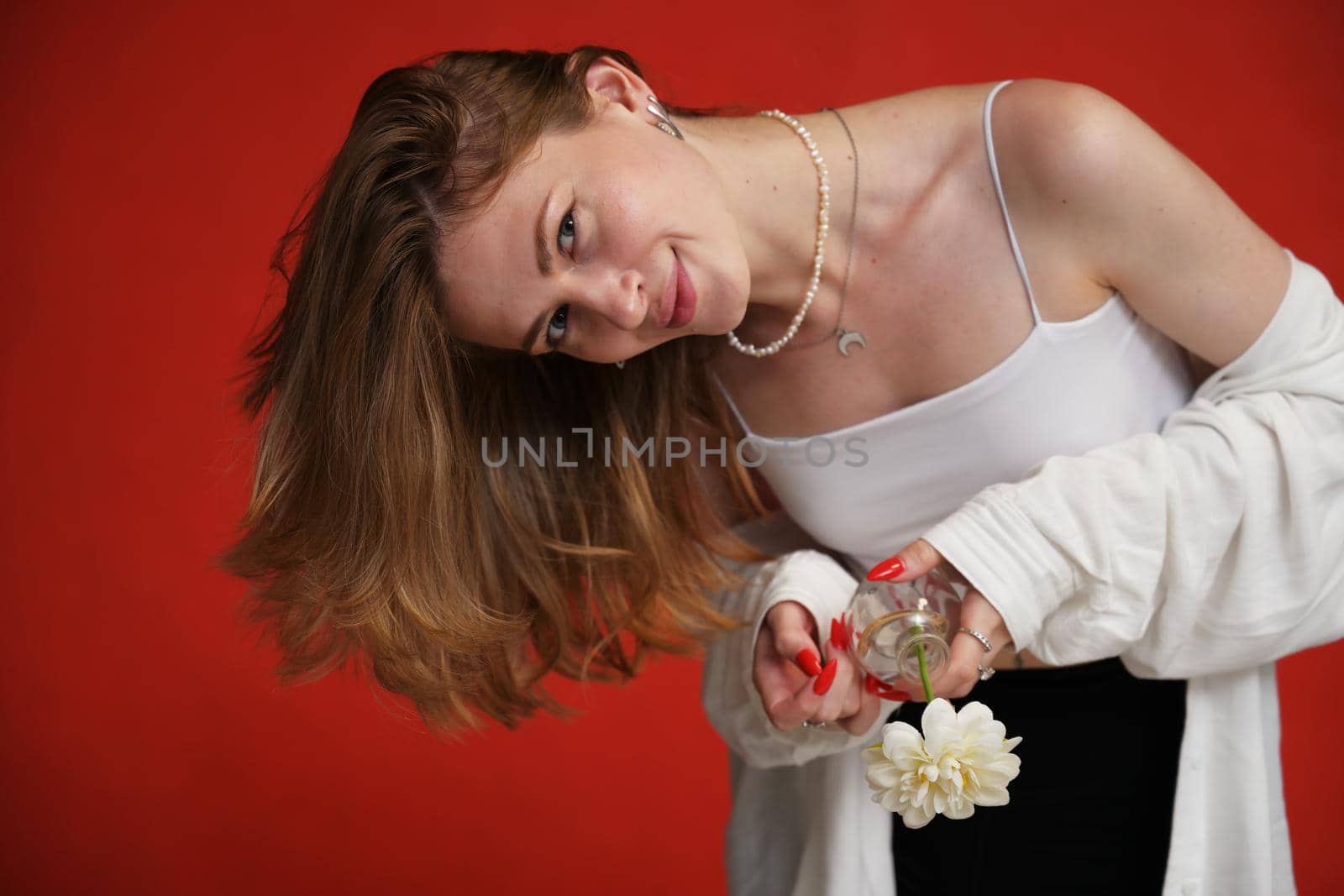 Smiling girl posing with flower in studio on red background by chichaevstudio