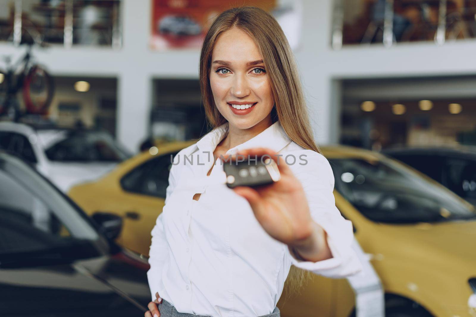 Young happy woman buyer/seller near the car with keys in hand close up